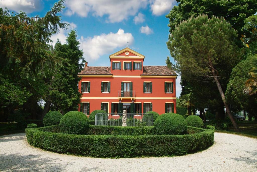 een groot oranje huis met een heg ervoor bij Locanda Da Piero in Mirano