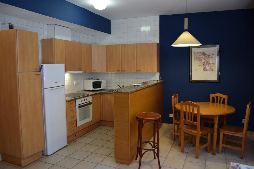 a kitchen with a table and a white refrigerator at Apartaments Bizantí in Sant Martí d'Empúries