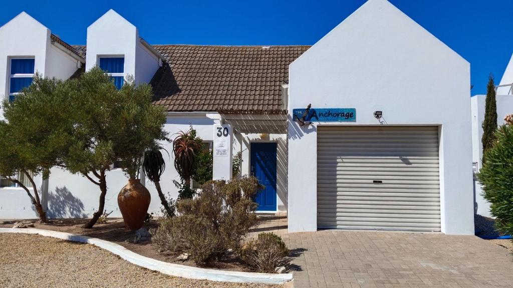 a white house with a garage in front of it at Anchorage in Stompneusbaai