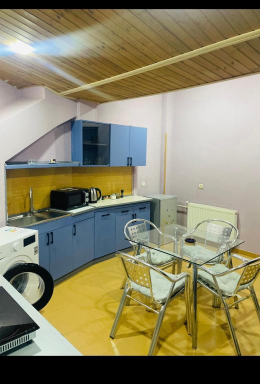 a kitchen with blue cabinets and a glass table and chairs at Tbilisi Vera in Tbilisi City