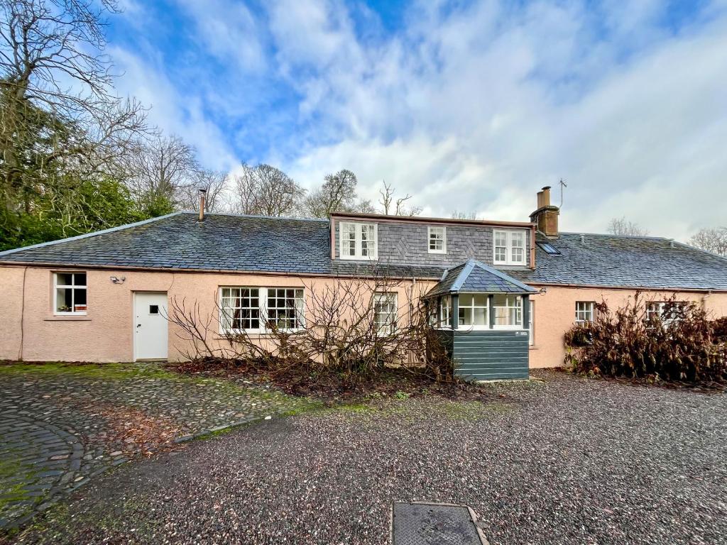 a large pink house with a driveway in front of it at Grieves Cottage - Uk50908 in Cupar