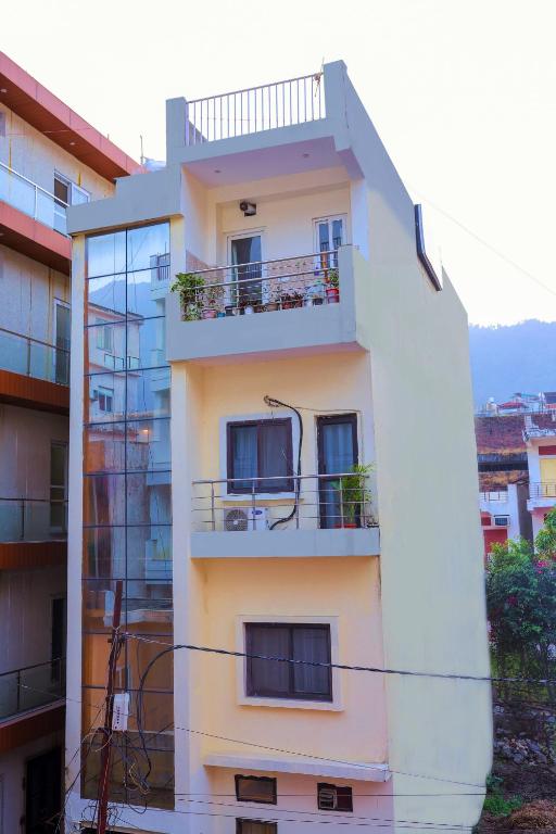 a white building with a balcony on the side of it at Hotel Pi-Tapovan in Rishīkesh