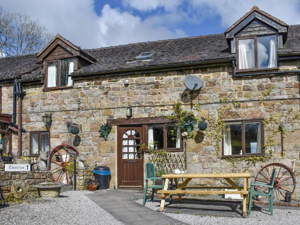an old stone house with a bench in front of it at Meadow Cottage in Leek