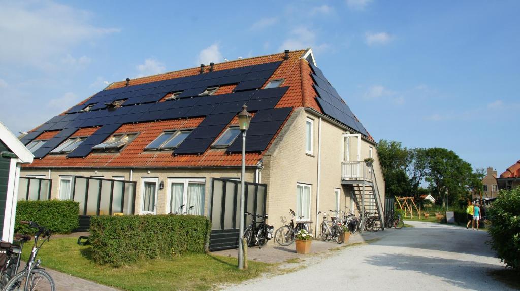 une maison avec des panneaux solaires sur le toit dans l'établissement Appartementenhotel Tjermelân Terschelling, à Oosterend
