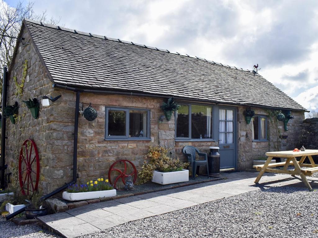 a small stone house with a picnic table in front of it at Stable Cottage in Leek