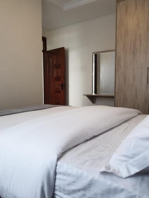 a large white bed in a room with a wooden cabinet at Cynergy Home in Nairobi