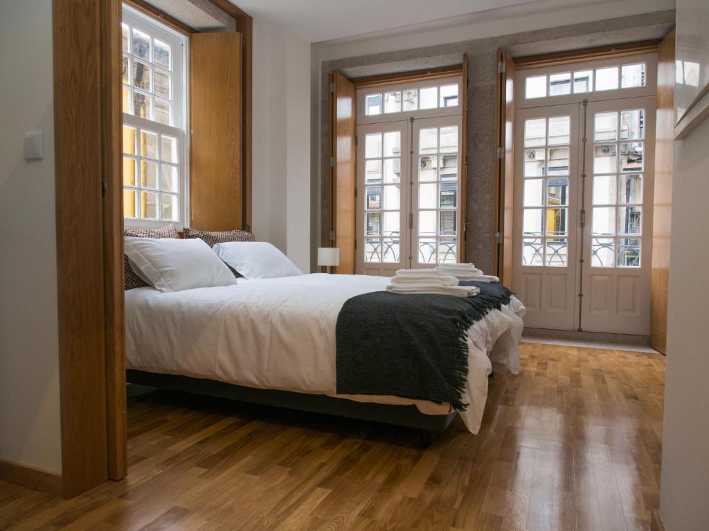 um quarto com uma cama grande e 2 janelas em Belomont6 Apartments no Porto