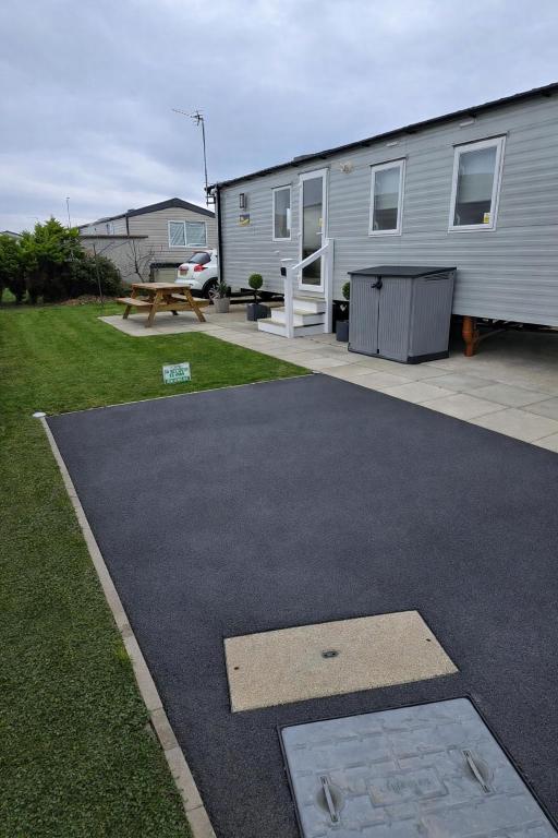 a house with a patio and a yard with a picnic table at 8 berth 3 Bedroomed CARAVAN Lyons Robin Hood Rhyl 17 Elm Crescent in Meliden
