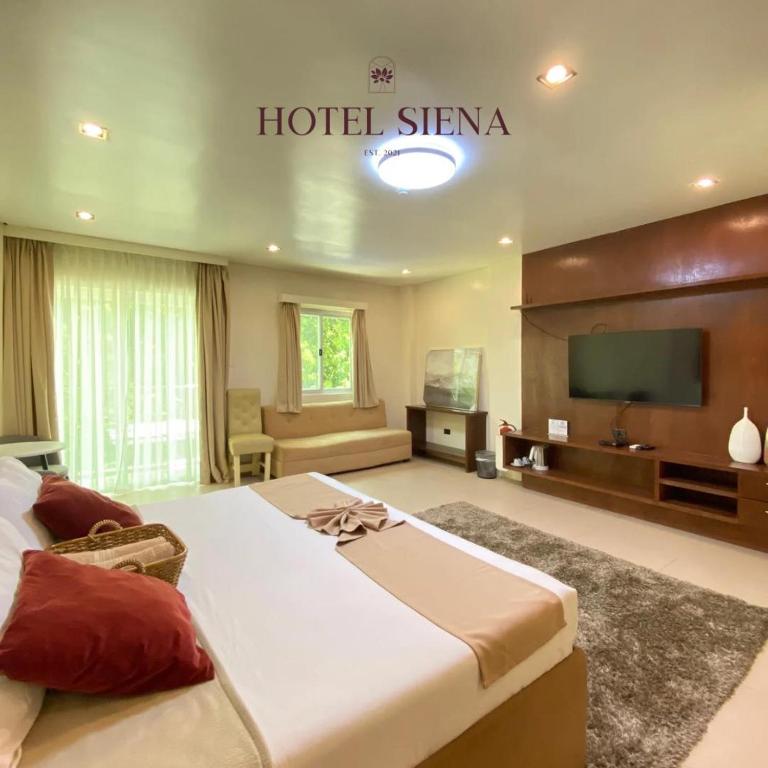a hotel bedroom with two beds and a flat screen tv at Hotel Siena in Sampong