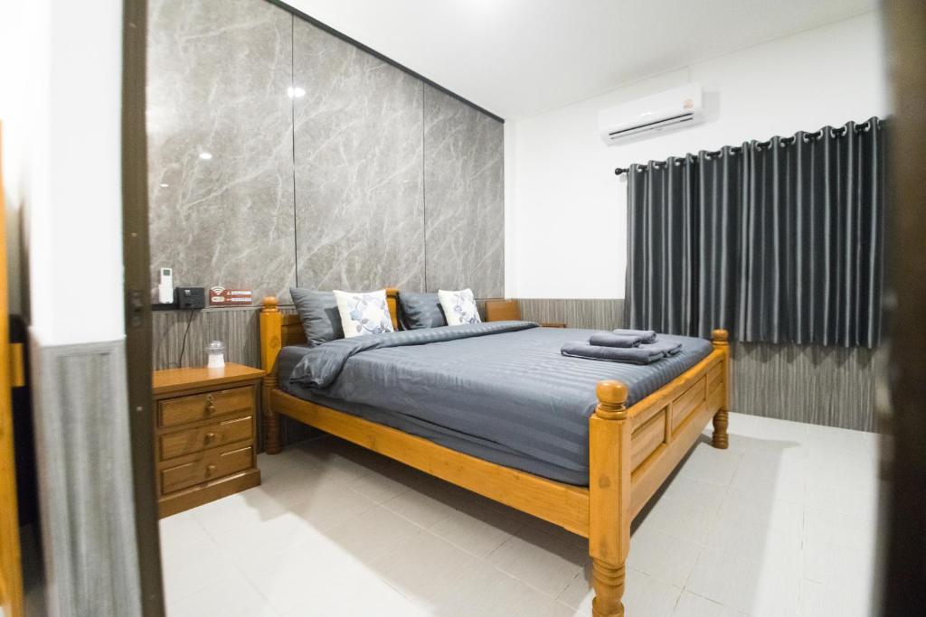 ein Schlafzimmer mit einem Holzbett und einer großen Wand in der Unterkunft บ้านคุณ เฮ้าส์ in Phrae