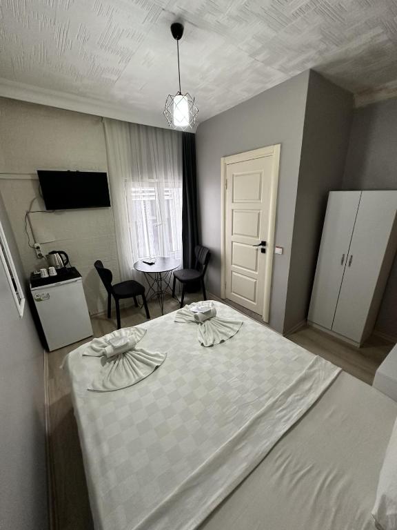 ein Zimmer mit einem weißen Bett, einem Tisch und Stühlen in der Unterkunft pars otel in Tuzla