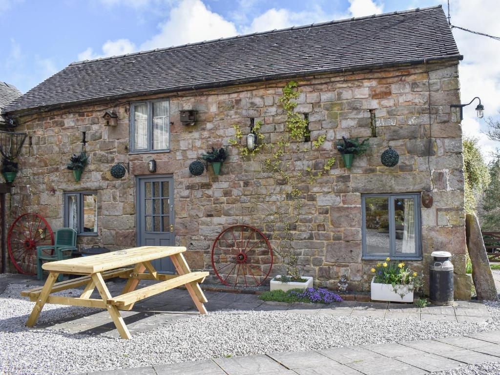 a wooden picnic table in front of a stone building at Swallow Cottage in Leek