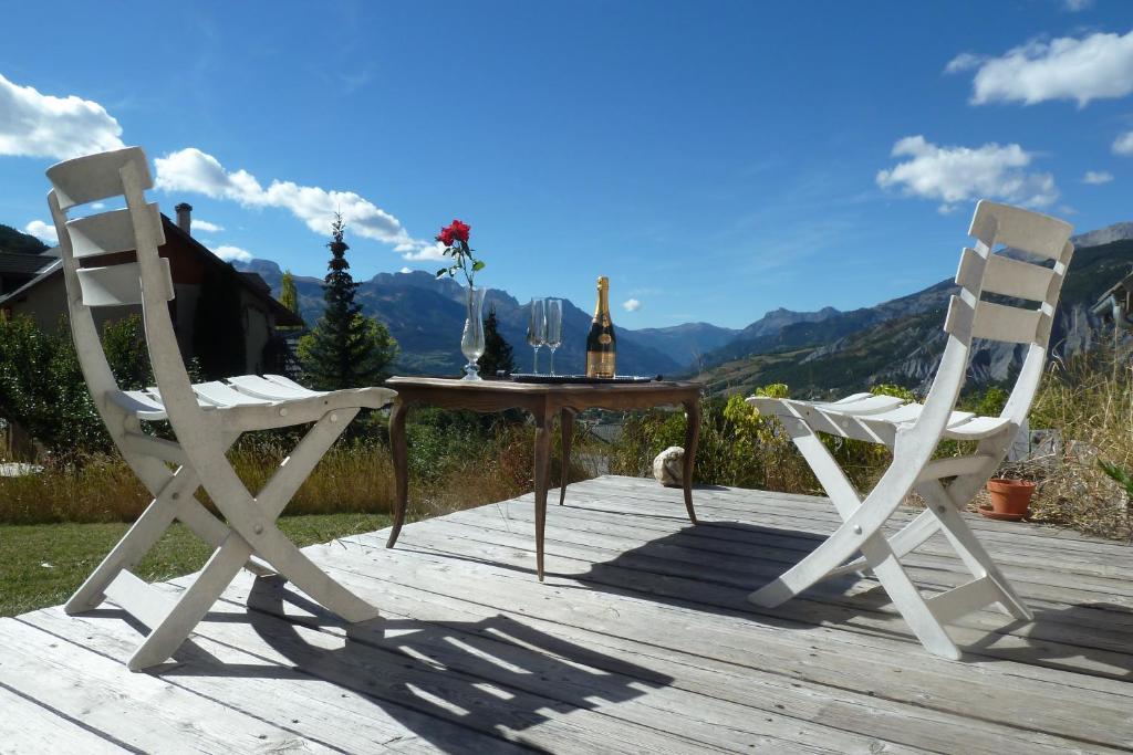 two chairs and a table on a wooden deck at Studio Barcelonnette Ubaye, Provence in Enchastrayes