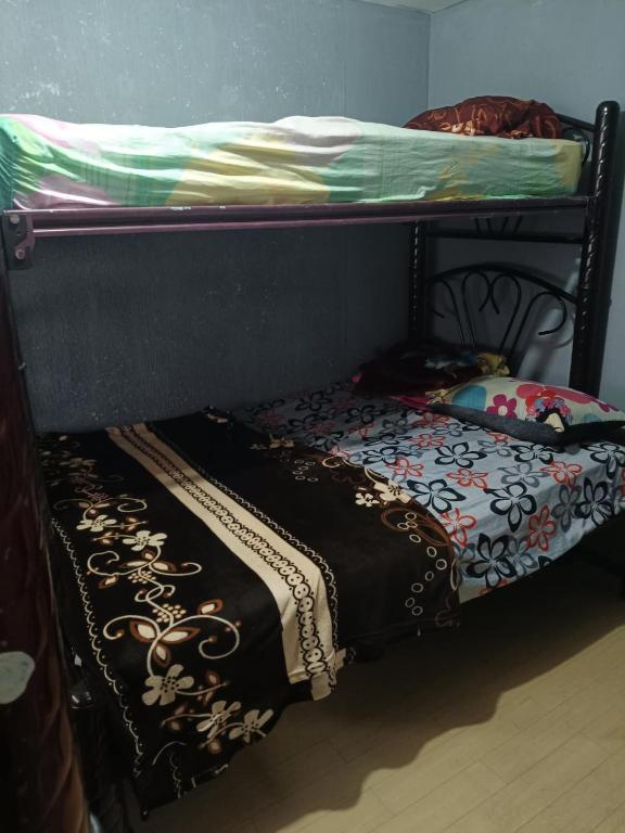 a bunk bed with a black frame and a bed with a blanket at La casa de Ile in San Juan Pueblo Nuevo