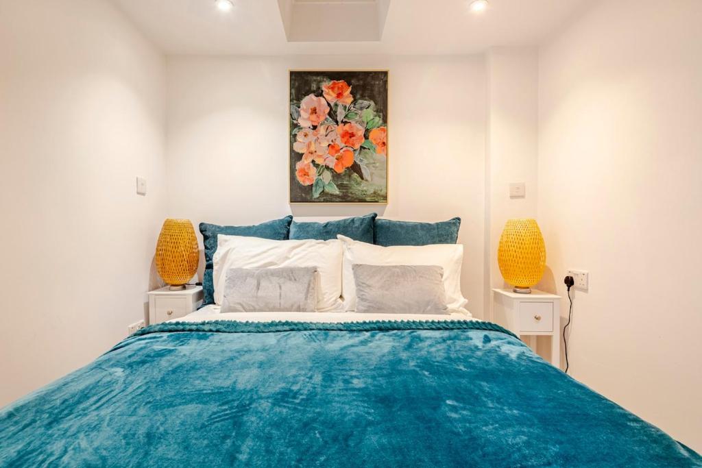 a bedroom with a blue bed and a painting on the wall at SkylightAnnex in Gaywood