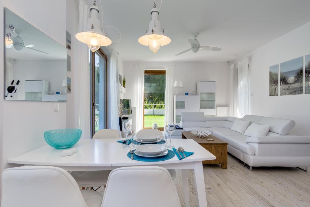 a white living room with a white table and chairs at Apartament Dani-Apart in Gdańsk