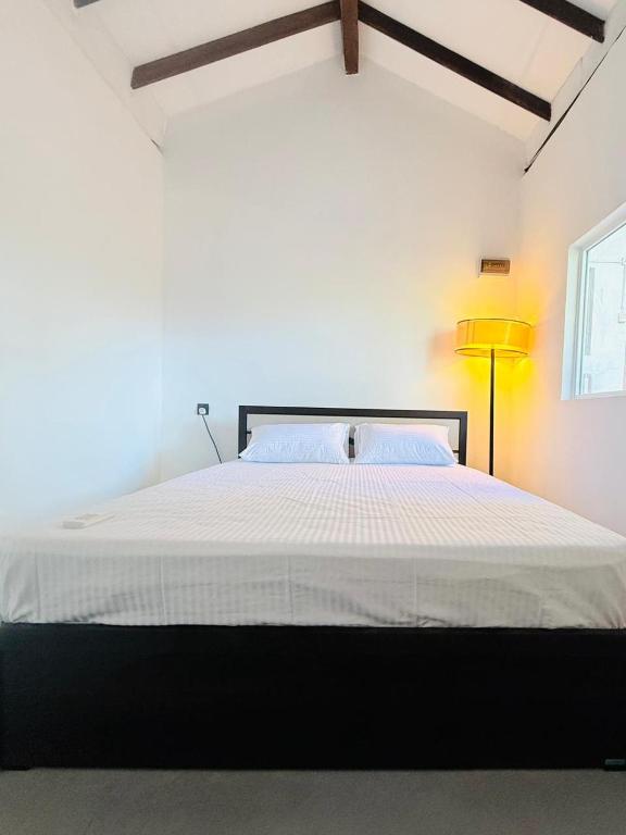 a bedroom with a large white bed with a lamp at Greenora Resort in Katunayaka