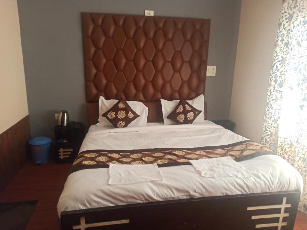 a bedroom with a large bed with a large headboard at Golf view resort in Pahalgām