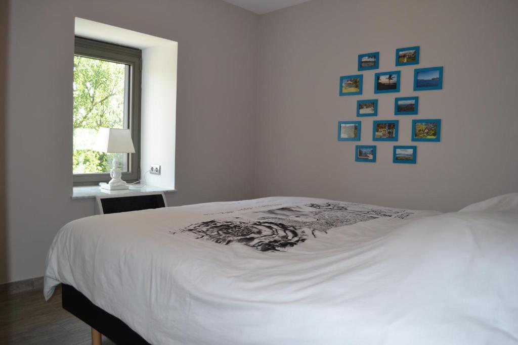 uma cama branca num quarto com fotografias na parede em Gîtes Paquay em Libramont