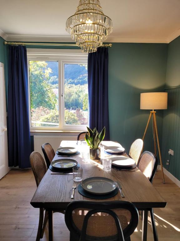 a dining room with a table with chairs and a chandelier at Riverside Home Kinlochleven in Kinlochleven