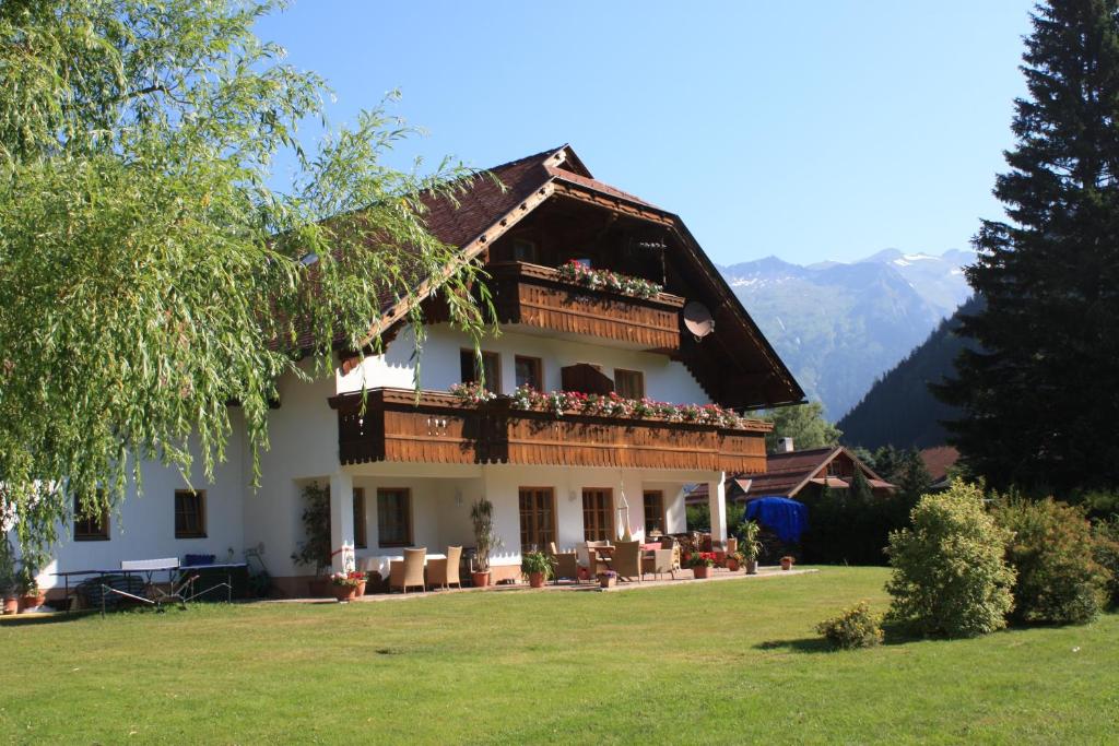 uma grande casa branca com uma varanda num relvado em Landhaus Rainer em Mallnitz