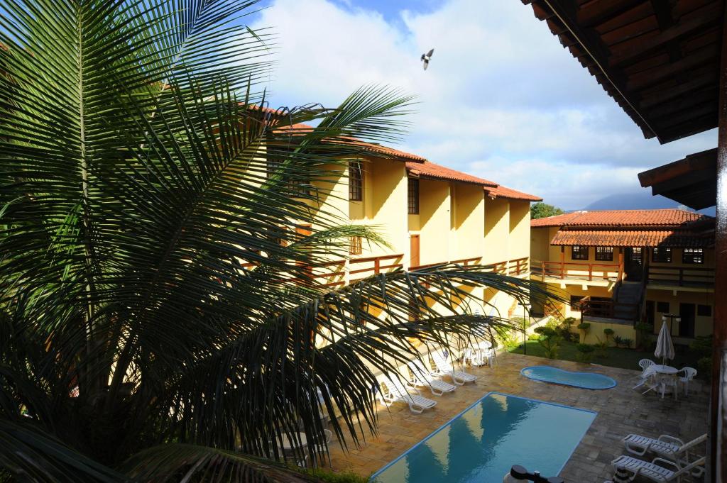 a palm tree in front of a house with a pool at Hotel da Ilha in Ilhabela