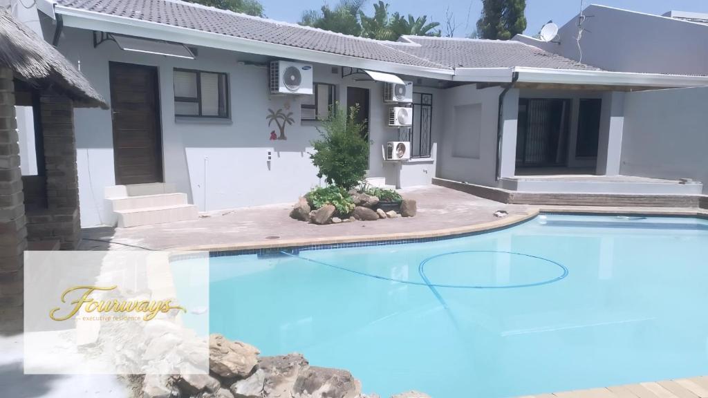 a house with a swimming pool in front of a house at Fourways Executive Residence in Four Ways