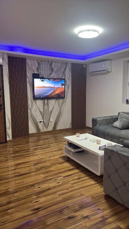 a living room with a couch and a tv on a wall at Apartmani AX in Pančevo