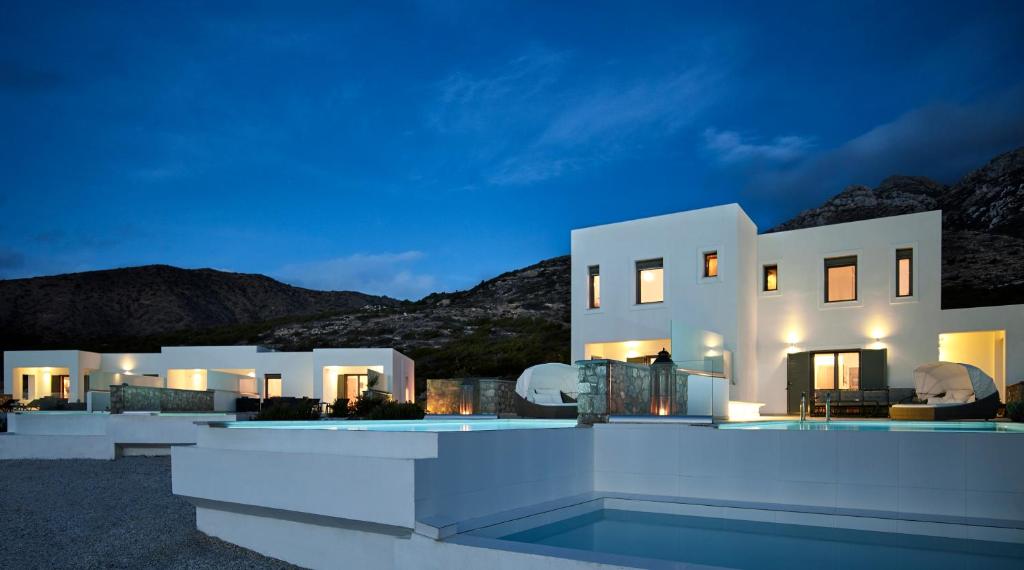 a large white house at night with mountains in the background at Arpathea Villas in Foiníkion