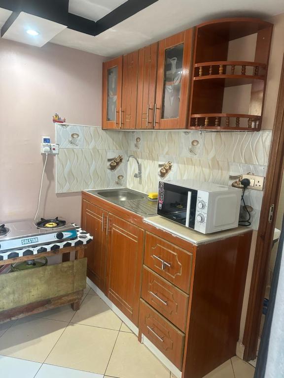 a kitchen with wooden cabinets and a microwave on a counter at Brighton court in Jomo Kenyatta Airport Nairobi