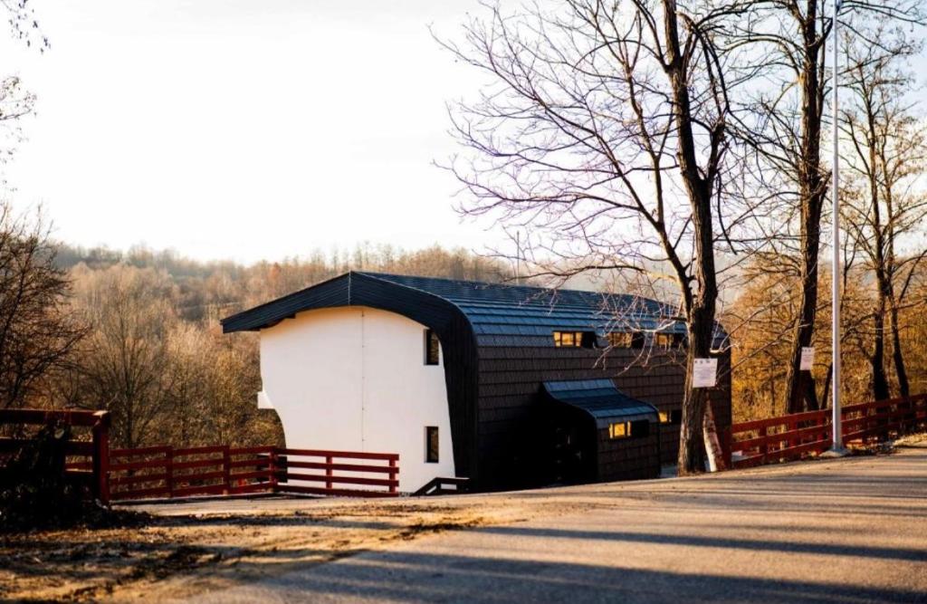 a black and white barn with a red fence at Ares Chalet in Horezu
