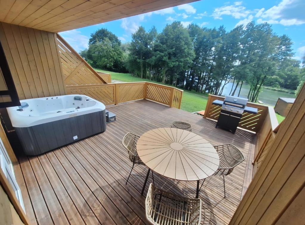 a deck with a hot tub and a table and chairs at Zatoka Warmii in Tomaszkowo