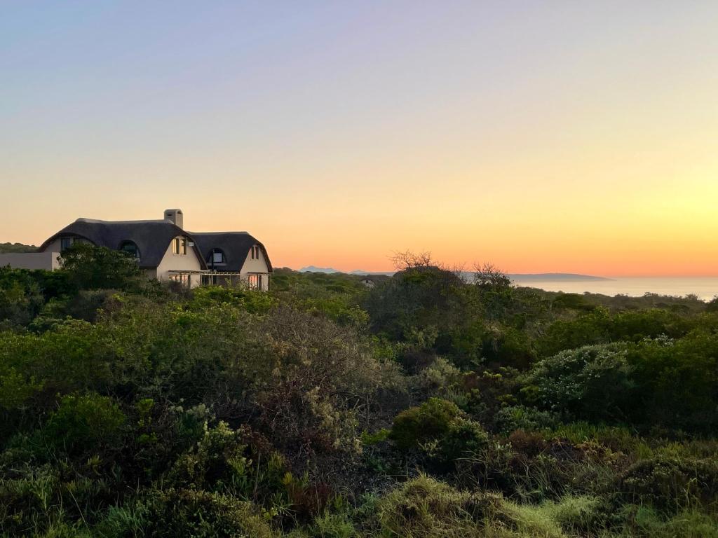 a house on a hill with the sunset in the background at Wild Comforts at Springerbaai in Boggomsbaai