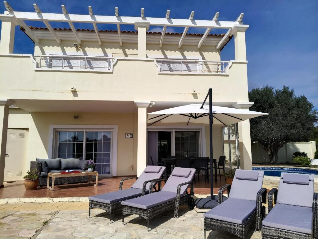 a patio with chairs and an umbrella in front of a house at Villa Elegante, with a private pool in Murcia
