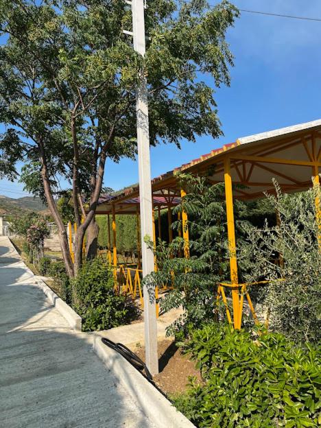 a building with yellow poles on the side of a road at Caco Camper Parking in Berat