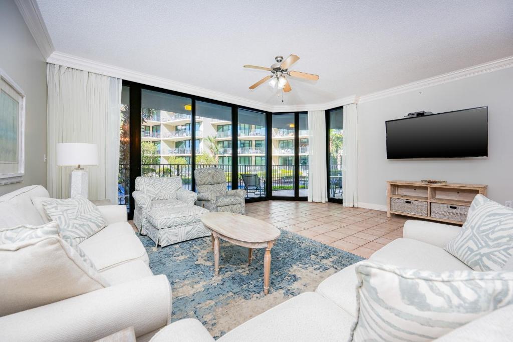 a living room with white furniture and a flat screen tv at Phoenix on the Bay 1124 in Orange Beach