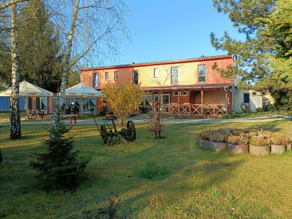 a large brick building with a yard with trees at Center Angelos in Bronków