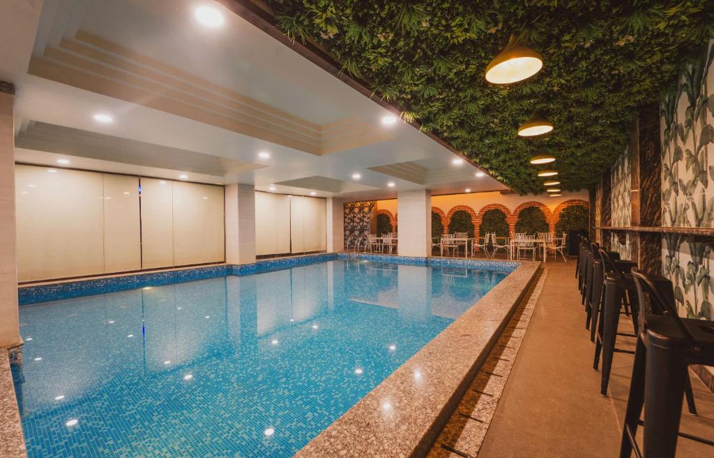 a large swimming pool with tables and chairs at Hotel Magenta-City Center Bani Park Jaipur in Jaipur