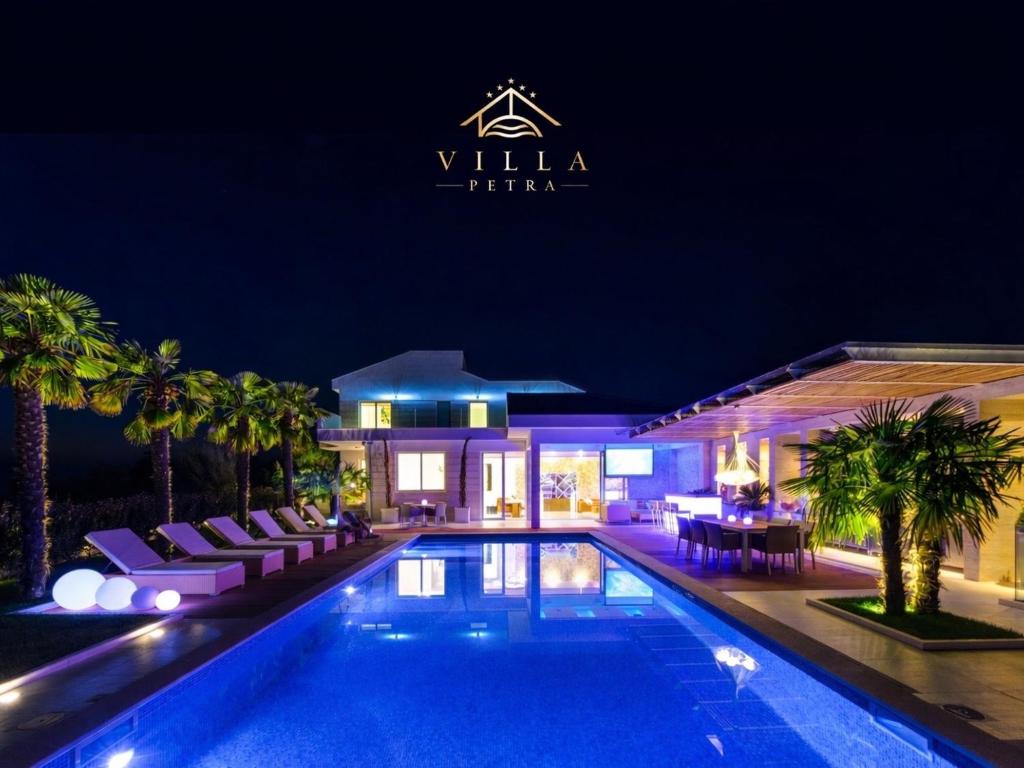 a villa with a swimming pool at night at Villa Petra, Luxury Villa & Private Yacht Experience near Zrće Beach, Pag in Novalja