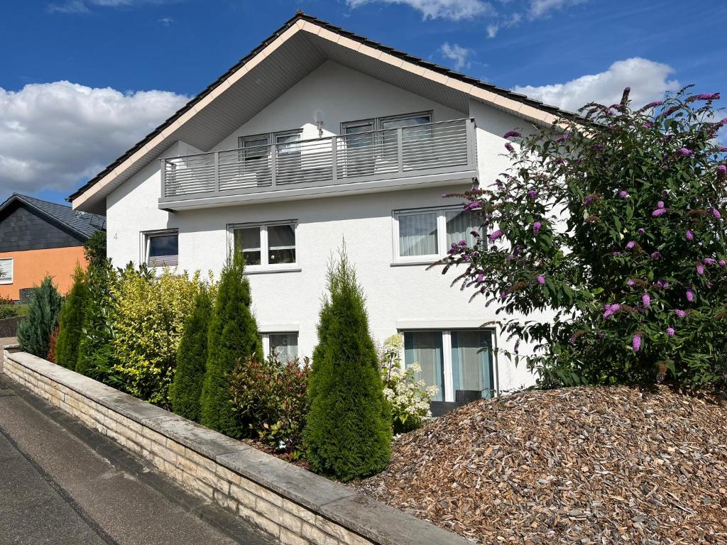 a white house with a balcony and some bushes at Haus Panorama in Massenbachhausen
