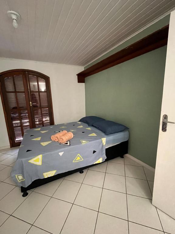 a bedroom with a bed with a blue comforter at Quarto em casa próx a rua das pedras in Búzios