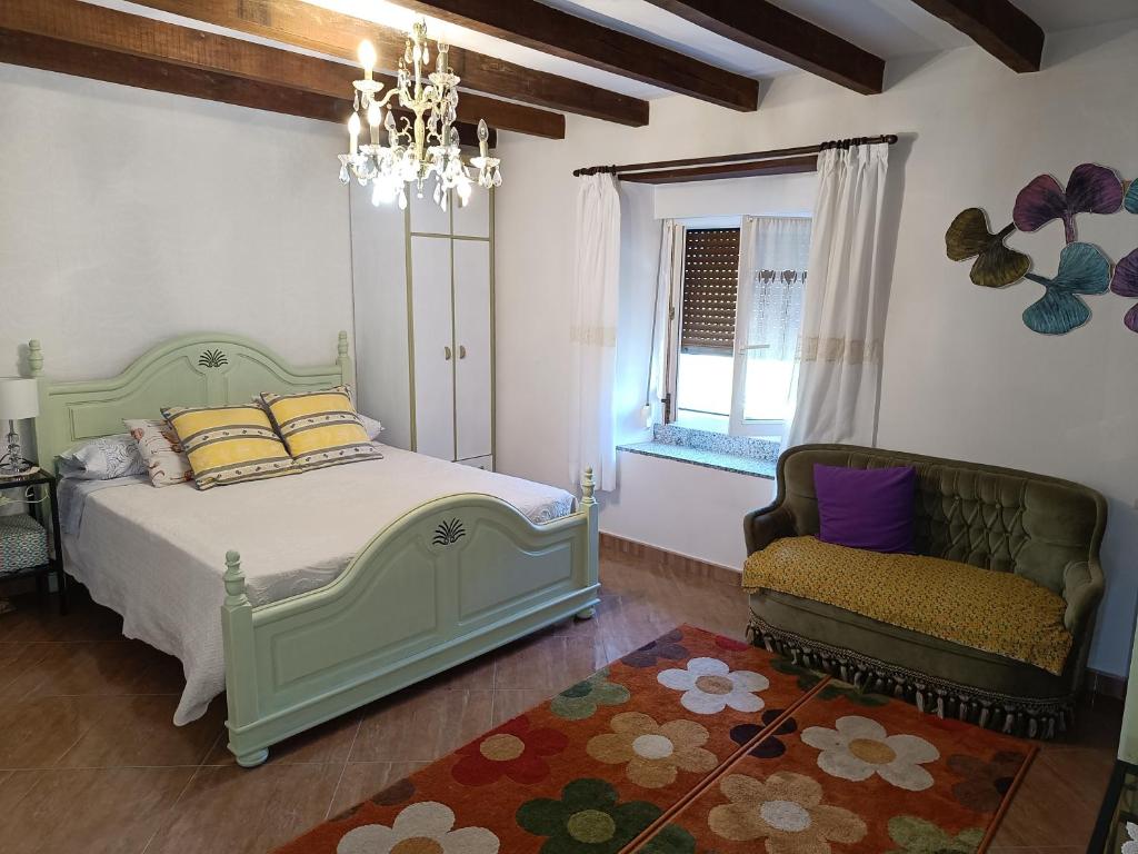 a bedroom with a bed and a chair and a window at El Caserio de Esther in Beranga