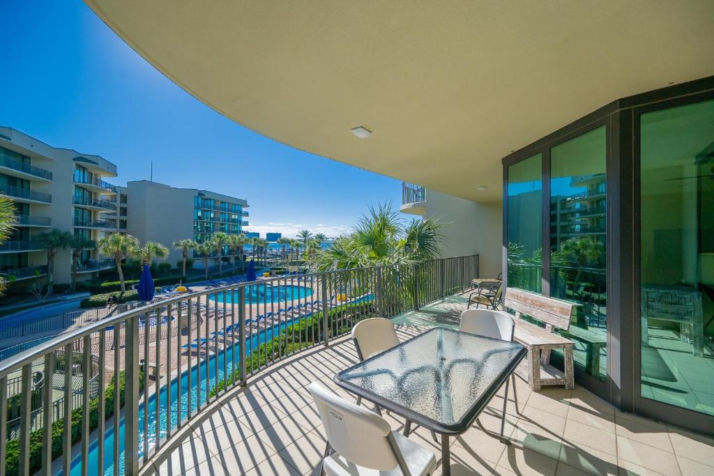 a balcony with a table and chairs and a pool at Phoenix on the Bay 1211 condo in Orange Beach