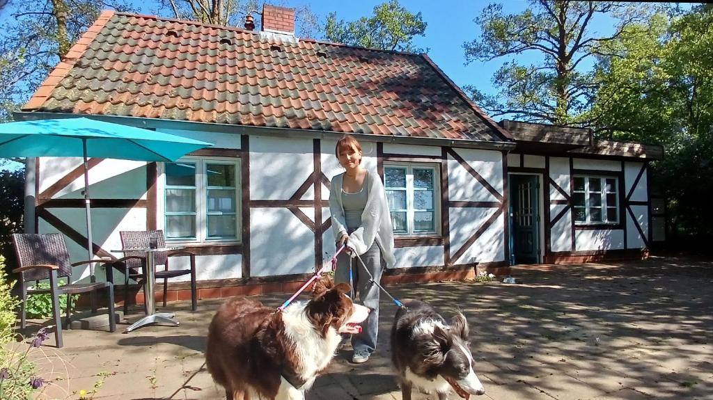 a woman with two dogs in front of a house at Ferienhaus Oppeln 21 in Wingst
