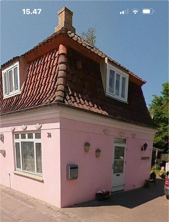 ein rosa Haus mit Dach an einer Straße in der Unterkunft Plads til 5 in Samsø