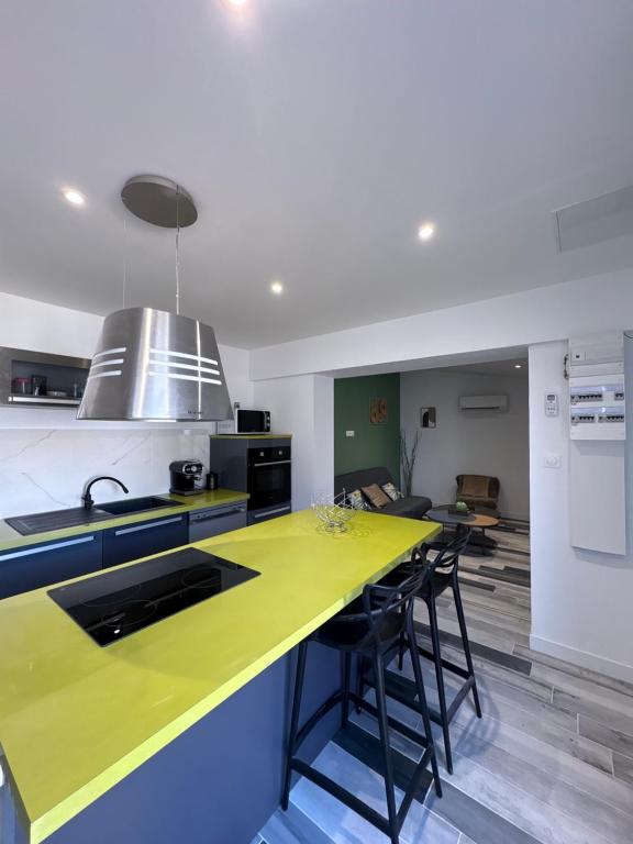 a kitchen with a yellow counter and some chairs at Lodge La Forêt in Les Sables-d'Olonne