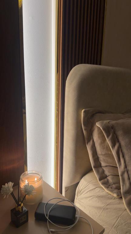 a candle on a table next to a bed at فله مع حديقه in Mukhaylīf