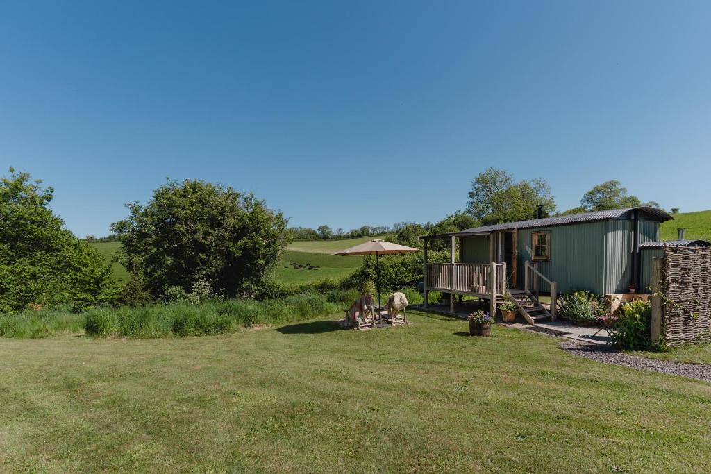 a house in a field with two dogs sitting in the yard at Hurdlemakers Hut in Dorchester