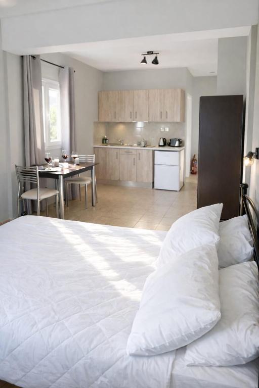 a bedroom with a white bed and a kitchen at Rodanthy II in Katelios