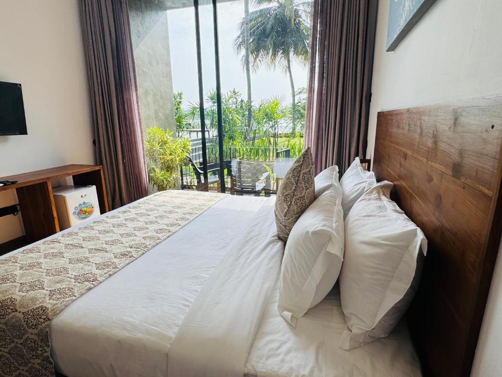 a bedroom with a bed with white pillows and a window at New Diyakawa Boutique Hotel in Nikawatawana